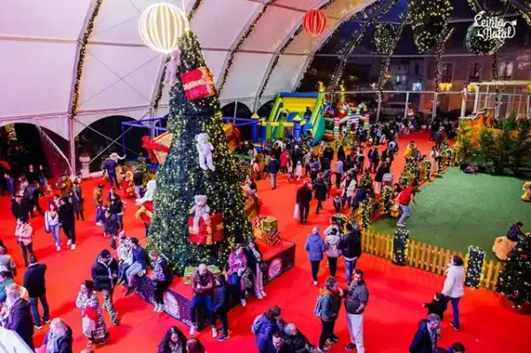 Vila de Natal coberta com árvore gigante, insufláveis e centenas de visitantes num evento municipal