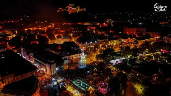 Vista aérea noturna de vila de Natal iluminada no centro histórico, com castelo ao fundo